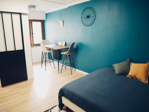 a bedroom with a blue wall with a table and chairs at Studio - WIFI - Train Station - Love Bridgi home in Forbach