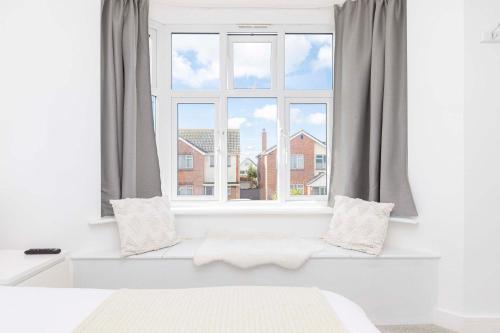 a bedroom with a window with a white bed and pillows at The White House - Lux Southbourne beach 3 bed stay in Southbourne