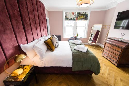 a bedroom with a large bed with a red wall at Dragon Villas - Harrogate in Harrogate
