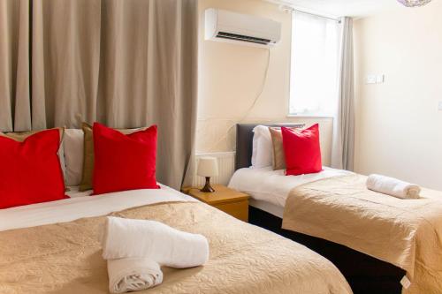 two beds in a room with red and white pillows at Spacious 5-Bedroom Home - Sleeps 11 & Free Parking in Tilbury