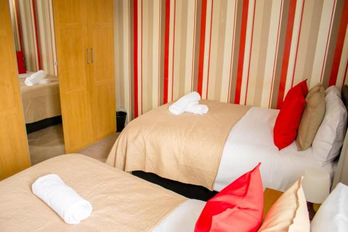 a hotel room with two beds with red and white pillows at Spacious 5-Bedroom Home - Sleeps 11 & Free Parking in Tilbury