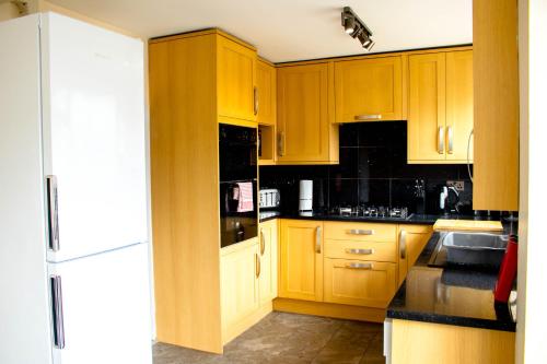a kitchen with wooden cabinets and a sink and a refrigerator at Spacious 5-Bed House! Tilbury! Free parking! in Tilbury