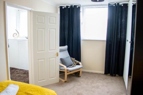 a bedroom with a blue chair and a window at Spacious 5-Bedroom Home - Sleeps 11 & Free Parking in Tilbury