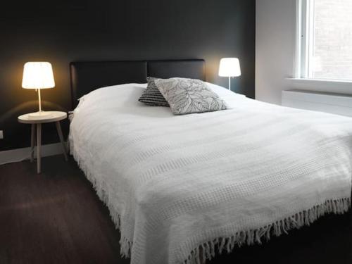 a bedroom with a large white bed with two lamps at Het Appense veld in Klarenbeek