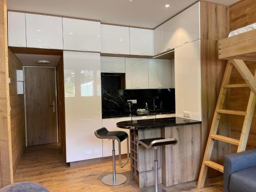 a kitchen with white cabinets and a bar with stools at Rendez-vous au studio in Valloire