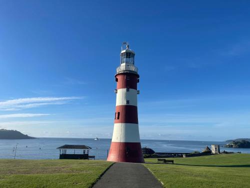 a red and white lighthouse sitting next to the ocean at Plymouth Barbican boutique luxury Apartment in Plymouth