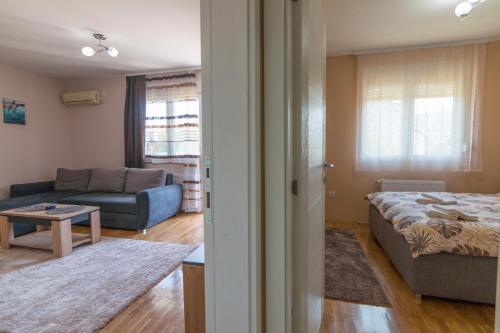 a room with a bed and a living room with a couch at Apartman Agin Kutak in Bajina Bašta