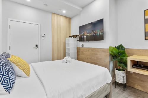 a bedroom with a white bed and a tv on the wall at Le Sand & Stone Hotel in Montréal