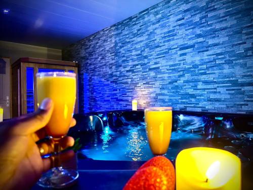 une personne tenant deux verres de jus d'orange dans un bain à remous dans l'établissement Charmant logement avec Spa, Sauna et terrasse, à Bergues