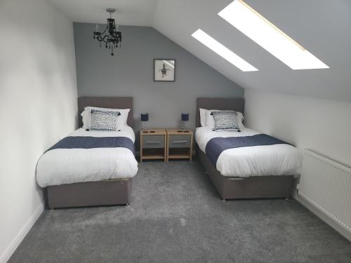 a attic room with two beds and a chandelier at Immaculate 7 Bed House in Ashton-under-Lyne OL7 in Manchester