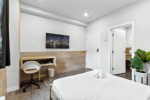 a bedroom with a bed and a desk and a tv at Le Sand & Stone Hotel in Montréal
