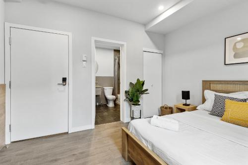 a white bedroom with a bed and a bathroom at Le Sand & Stone Hotel in Montréal
