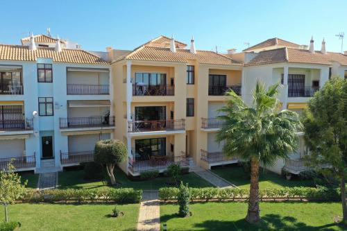 an apartment building with a palm tree in the foreground at Beach Apartment Villa Columbus in Vilamoura