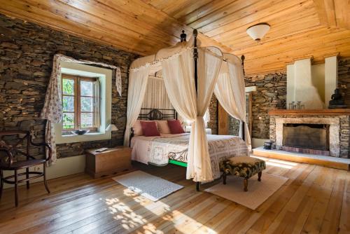 um quarto com uma cama de dossel e uma lareira em R3 Service - Quinta da Melroa - Mountain Villa em Viseu