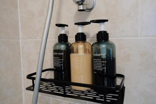 a rack with three shampoo bottles in a bathroom at Bee Stays - Byron House in Manchester