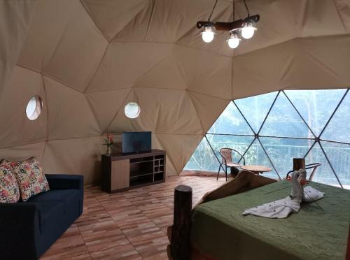 Cette chambre comprend une tente avec un lit et une télévision. dans l'établissement Tree houses Bosque Nuboso Monteverde, à Monteverde Costa Rica