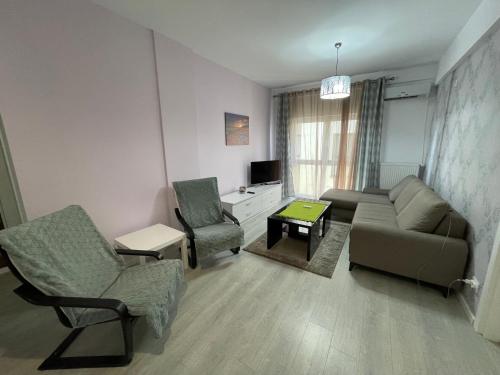 a living room with a couch and chairs and a tv at Toscana Apartments in Otopeni