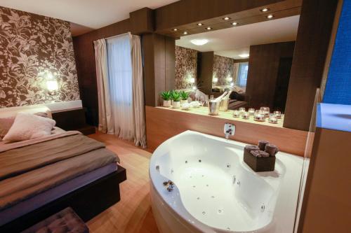 a bathroom with a bath tub next to a bed at Penzion Solid Spa in Mladá Boleslav