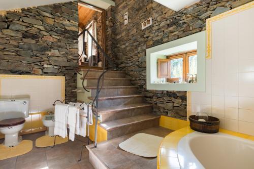 y baño con bañera y pared de piedra. en R3 Service - Quinta da Melroa - Mountain Villa, en Viseu