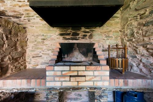 a stone fireplace in a stone building with a cross at T3 Quinta da Melroa - Mountain Villa - Caramulo in Viseu