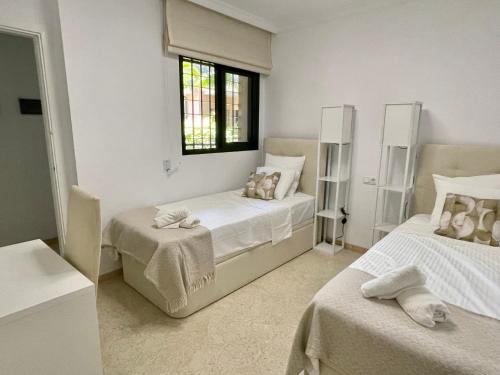 a white bedroom with two beds and a window at Royal Pearl Marbella in Marbella