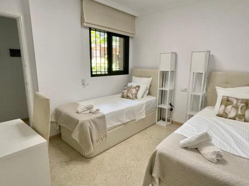 1 dormitorio blanco con 2 camas y ventana en Royal Pearl Marbella, en Marbella