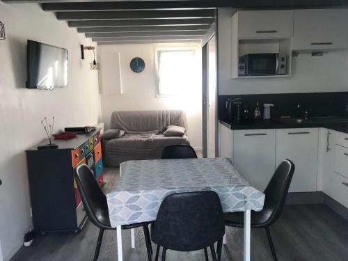 een keuken en een tafel en stoelen in een kamer bij Petite maison avec piscine à 500m de la plage in Guidel