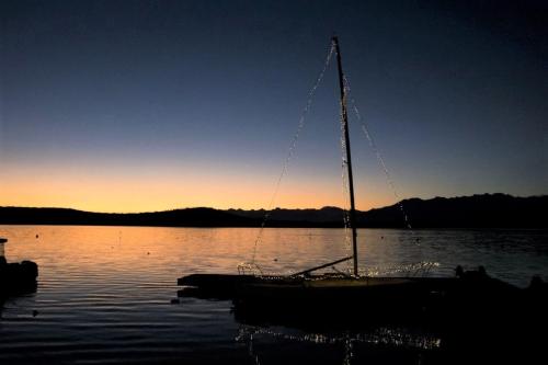 a sail boat sitting in the water at sunset at Appartamento doppi bagni sei posti letto in Viverone
