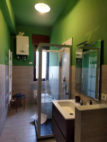 a green bathroom with a sink and a shower at Appartamento doppi bagni sei posti letto in Viverone