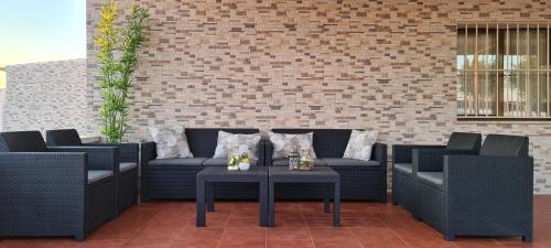 um pátio com cadeiras e mesas e uma parede de tijolos em Casa Rural Kentia em Valdepeñas