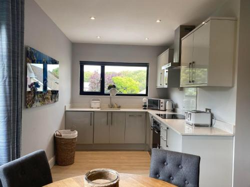 a kitchen with white cabinets and a table and a window at The Annexe Porthcawl Pet Friendly 2 Bedroom Flat with King Size bed bunk beds and sofa bed sleeps up to 5 people in Nottage