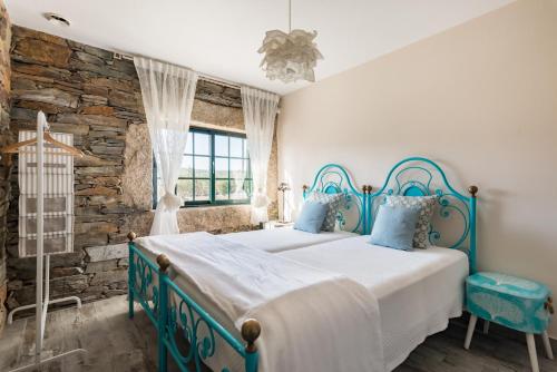 a bedroom with a blue and white bed and a stone wall at T3 com Piscina e Jardim - Casula no Caramulo in Tondela