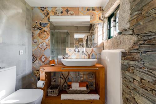 uma casa de banho com um lavatório e uma parede de pedra em R3 Service - Casula no Caramulo em Tondela