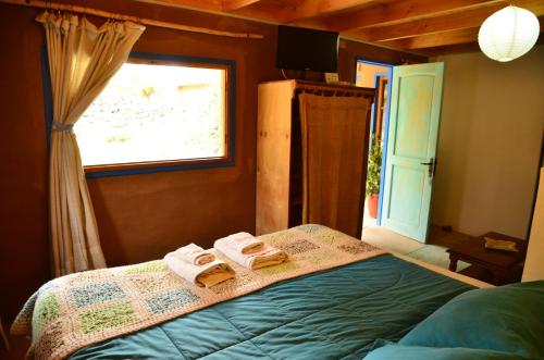 a bedroom with two towels on a bed with a window at Cabañas AHOPIEDRA in Vicuña