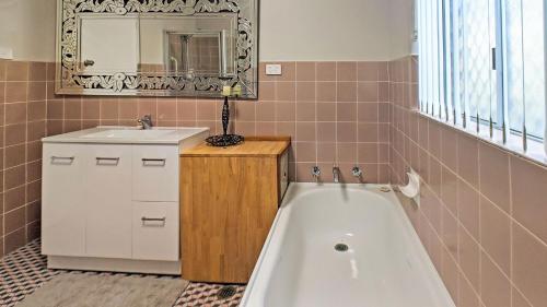 a bathroom with a tub and a sink and a mirror at Poseidons Hideaway by Experience Jervis Bay in Vincentia