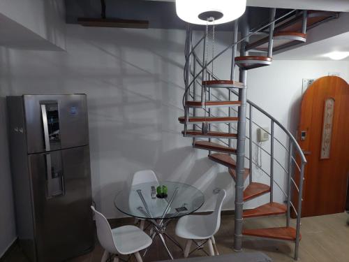 escalera de caracol en una habitación con mesa de cristal y sillas en Apartamento dúplex vacacional cerca a la playa, en Gaira