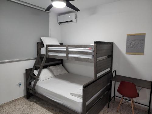 a bunk bed room with two bunk beds and a chair at Cozy apartment in the heart of the city in Ponce