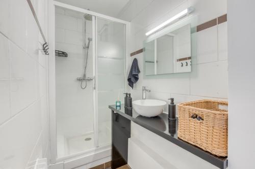 y baño blanco con lavabo y ducha. en Détente et Confort proche Paris et Orly, en Choisy-le-Roi
