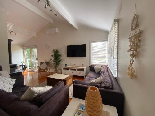 uma sala de estar com 2 sofás e uma televisão de ecrã plano em Invy Escape em Inverloch