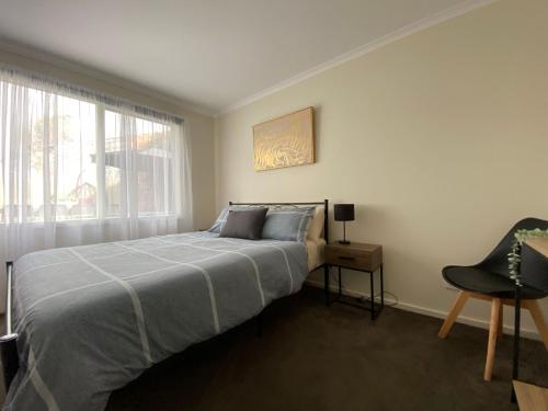 um quarto com uma cama, uma cadeira e uma janela em Invy Escape em Inverloch