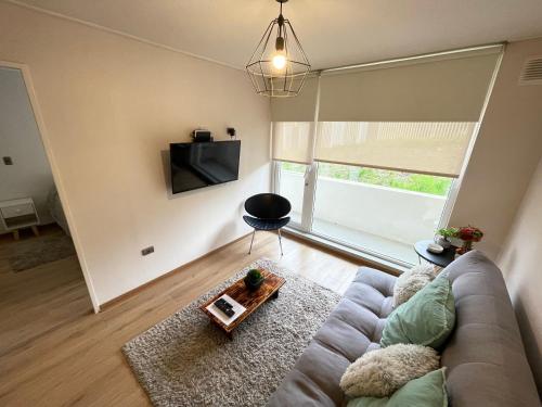 sala de estar con sofá y TV en Apartamento en exclusivo barrio Lomas de san Andrés con estacionamiento en Concepción