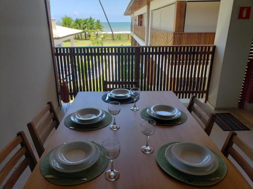 a table with plates and wine glasses on a balcony at Itacimirim - Duplex Aconchegante, Pé na Areia in Itacimirim