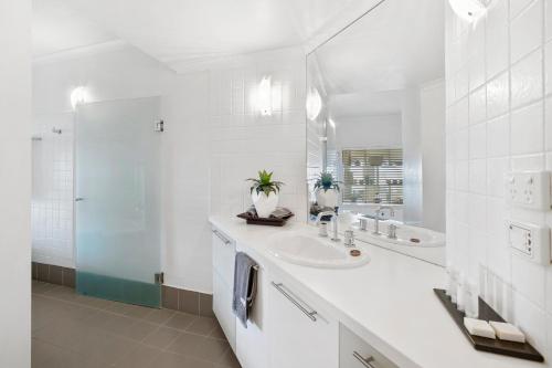W białej łazience znajduje się umywalka i lustro. w obiekcie Lorne Beachfront Accommodation w mieście Lorne