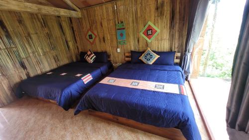 a bedroom with two beds in a log cabin at Toong homestay in Ha Giang