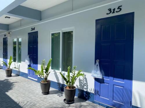a building with blue doors and potted plants at Baan Nuk Anong in Chiang Rai