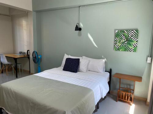 Un dormitorio con una gran cama blanca y una mesa en Baan Nukanong Guesthouse en Chiang Rai