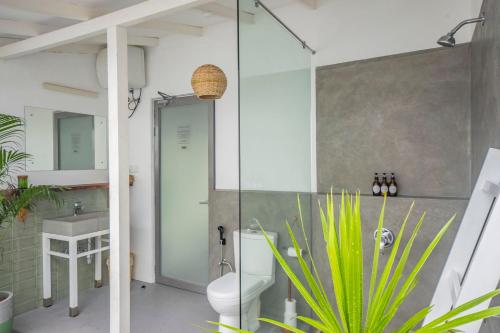 a bathroom with a shower and a toilet and a sink at Global Surf Lodge Kabalana in Ahangama