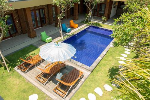 - un parasol et des chaises à côté de la piscine dans l'établissement Frangipani House and Spa by ecommerceloka, à Canggu