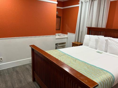 a bedroom with a bed with white sheets and orange walls at Americas Best Value Inn Royal Carriage in Jamestown