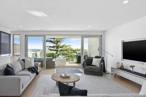 a living room with a couch and a tv at Beachside Living with Sea Views at the Pines in Ocean Grove